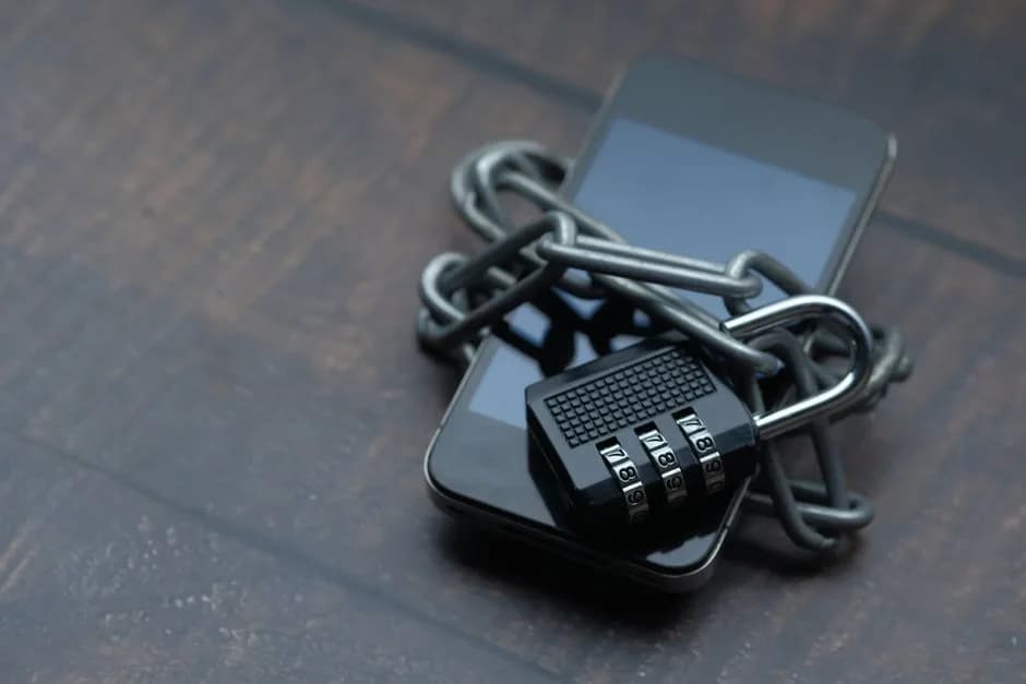 Close-up of a smartphone wrapped in a chain with a padlock