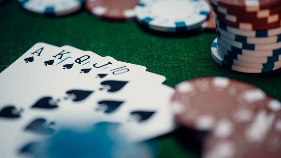 Close-up of a royal flush poker hand surrounded by colorful chips on a green table