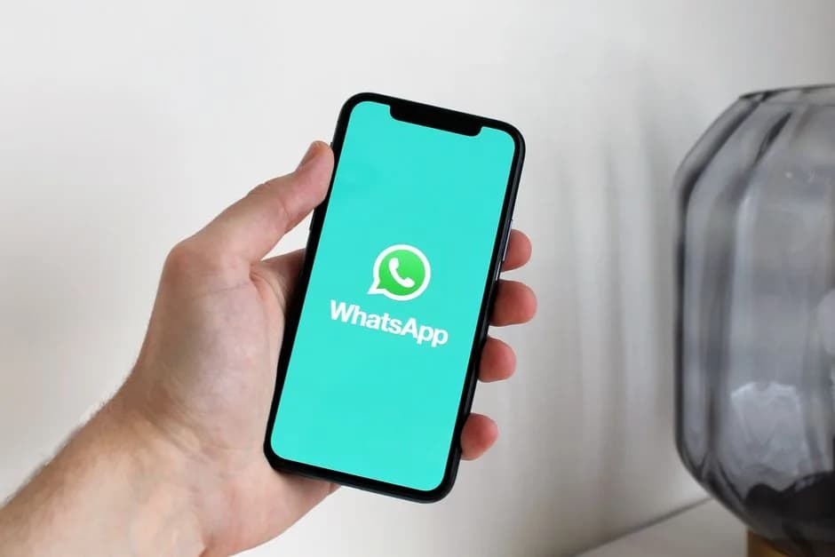 Close-up of a hand holding a smartphone displaying the WhatsApp app screen