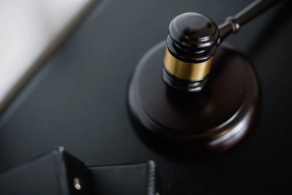 Overhead view of a wooden gavel on round surface near folders in a courtroom
