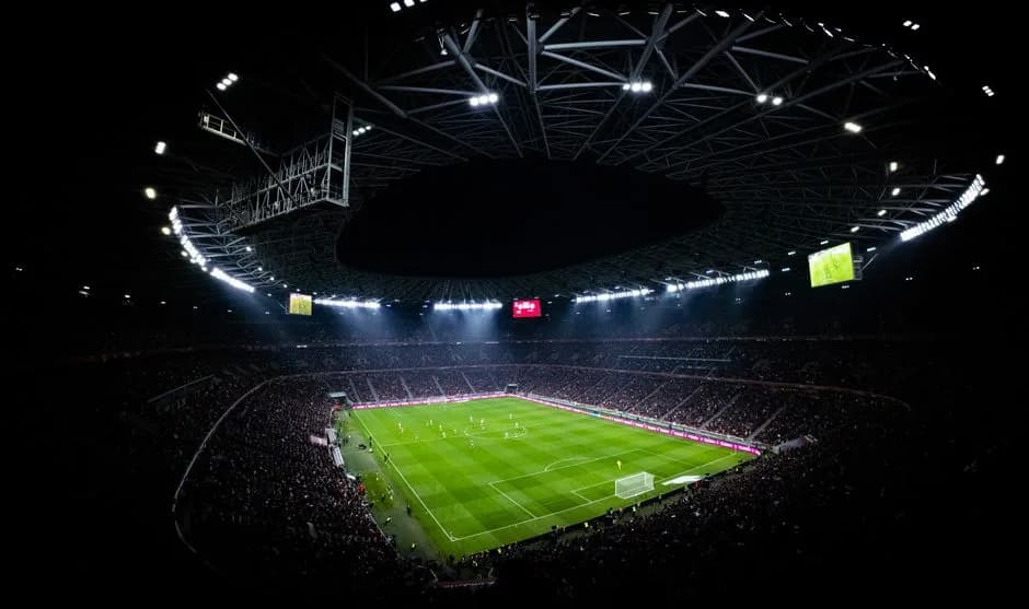 Aerial view of a night football match at an illuminated stadium in Budapest with packed stands