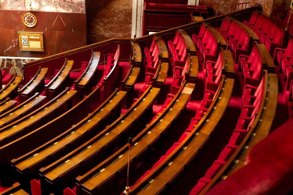 Legislative chamber with curved red seating and wooden desks