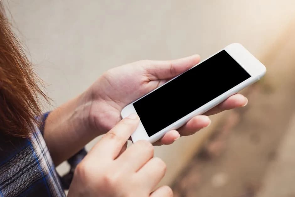 Person holding and using a smartphone outdoors, focusing on hands and screen