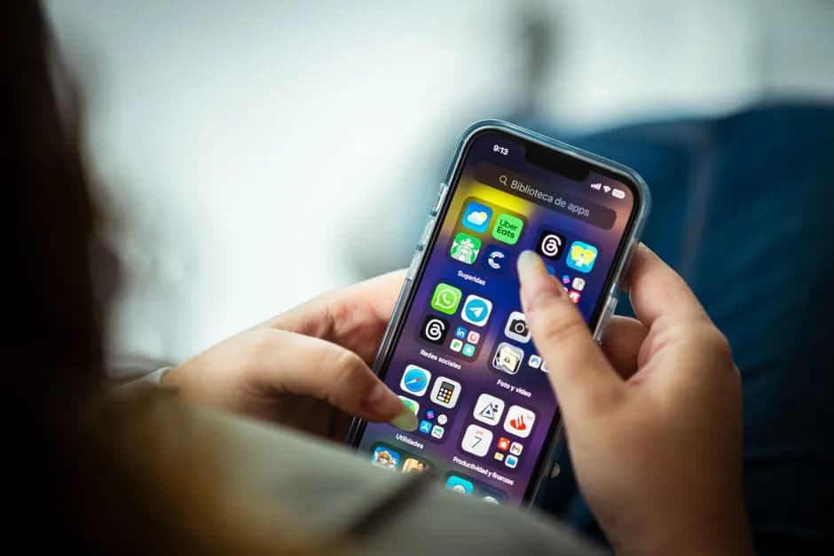 Close-up of a woman holding a smartphone displaying various apps