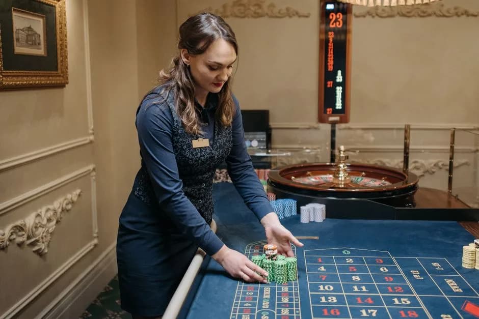 Female casino dealer arranging poker chips on a roulette table in an elegant casino setting