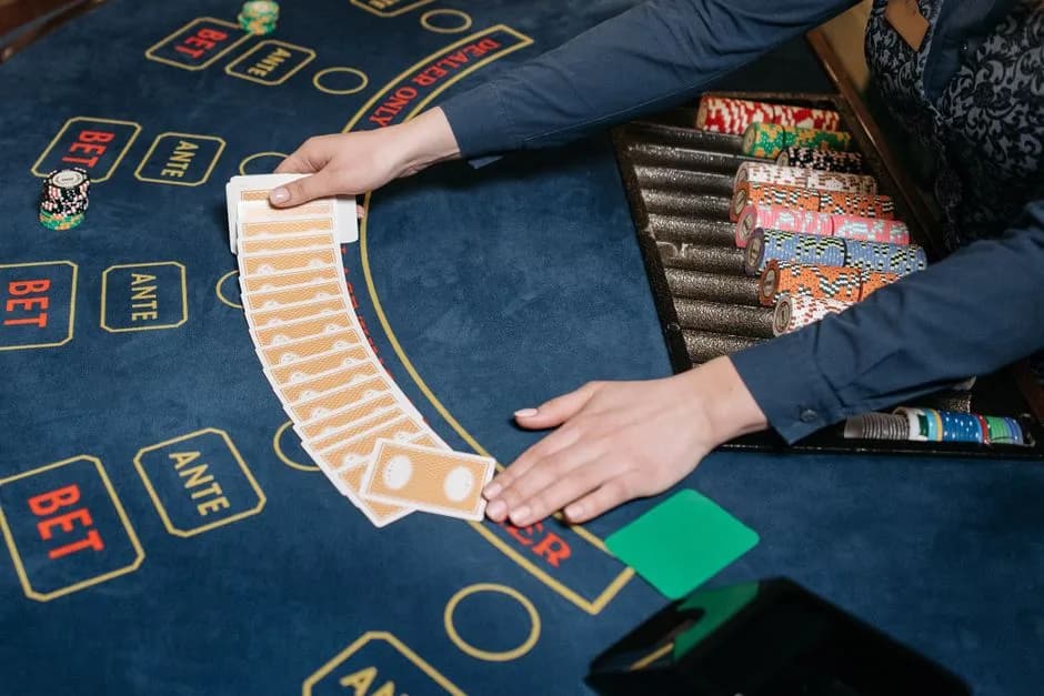 Casino dealer spreading playing cards on a gaming table with colourful chips