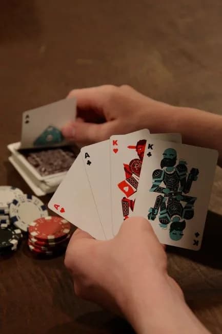 Close-up of hands holding aces and kings with poker chips on the table