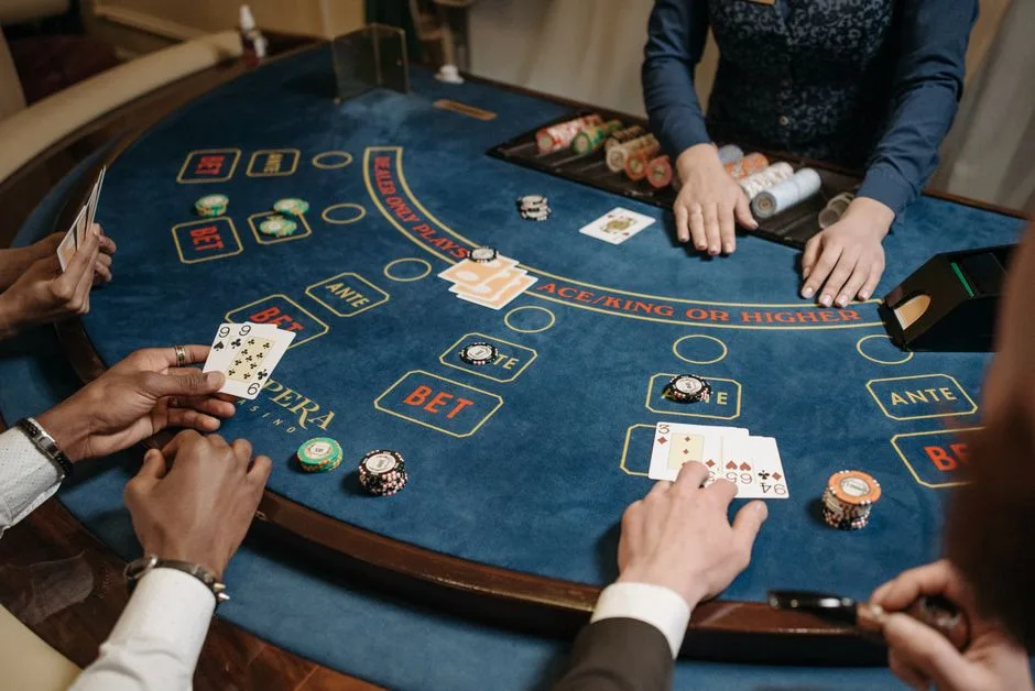 Players gathered around a casino table playing a lively card game with chips in view