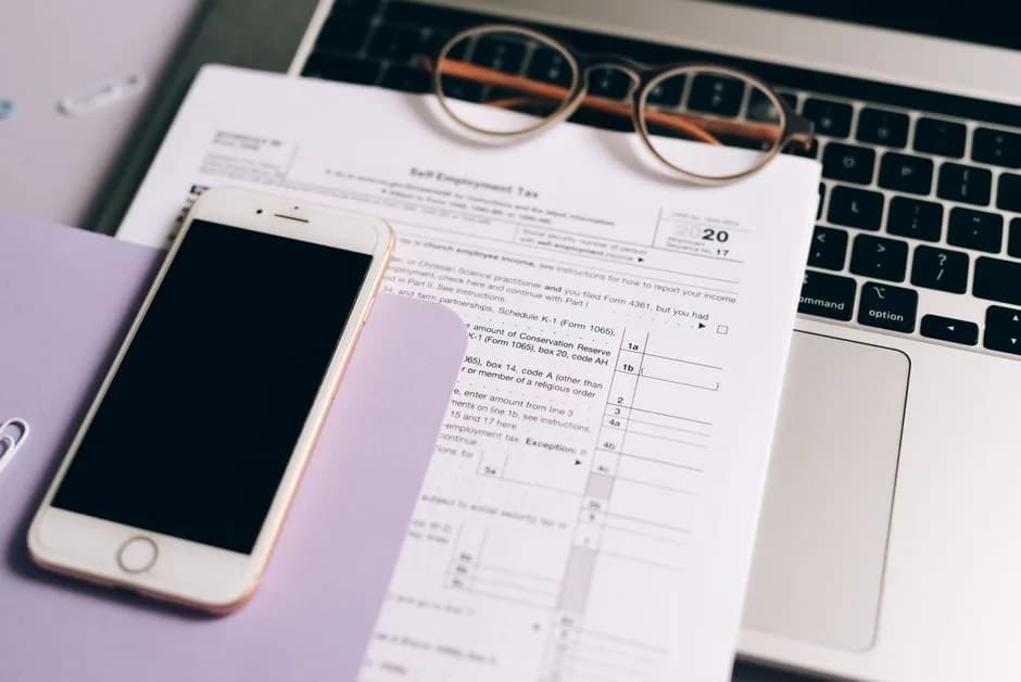 Tax documents with laptop and smartphone on a desk