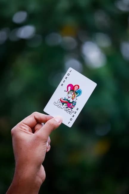 A hand holding a Joker playing card