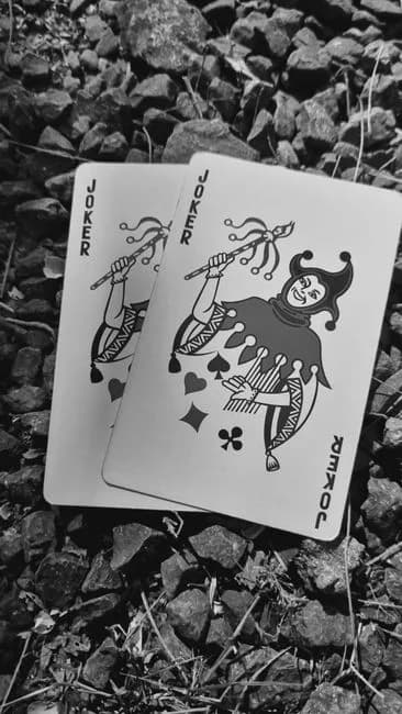 Two Joker playing cards on a gravel surface