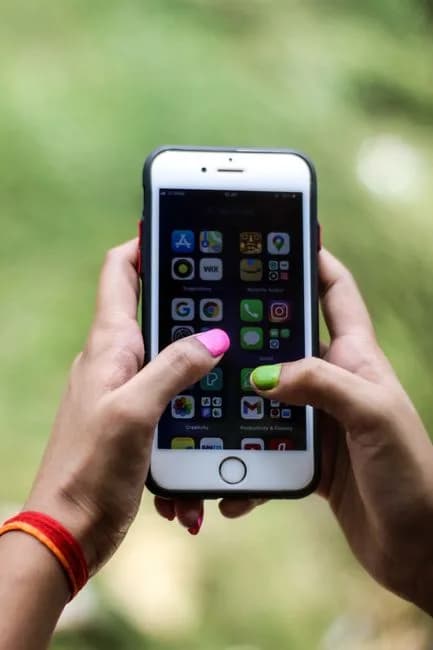Close-up of a person holding a smartphone displaying various applications