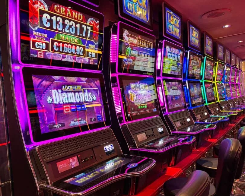 Colorful slot machines lined up in a casino with neon lights and jackpot displays