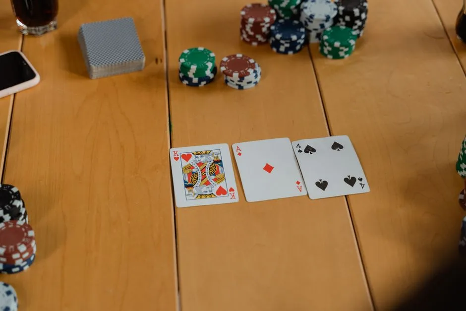 Playing cards spread on a wooden table alongside casino chips