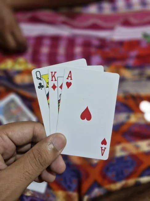 A hand holding a strong set of playing cards against a colorful background