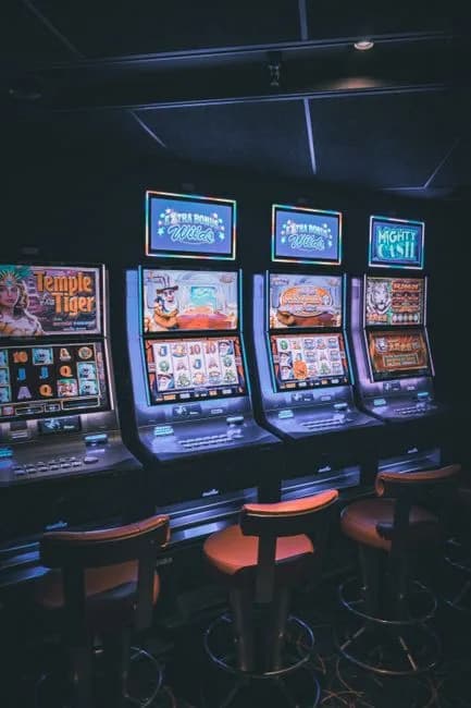 Row of illuminated slot machines in a dimly lit empty casino area